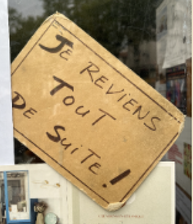 Worn handwritten cardboard sign in a shop window reading "Je reviens tout de suite!" (French for "I'll be right back!")